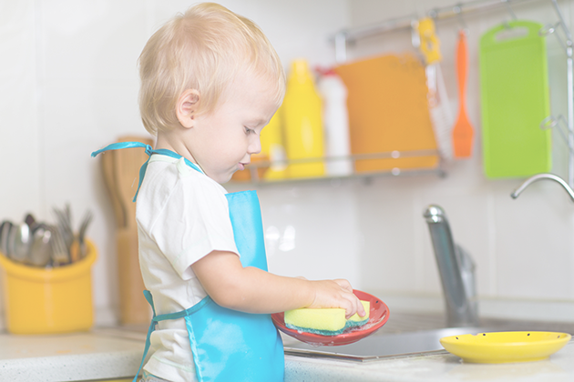 Preschool blonde boy cleaning dishes